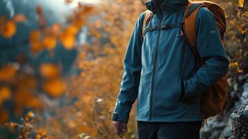 Mountain trail scene with a hiker in a fleece jacket, surrounded by colorful autumn leaves, breath visible in the crisp autumn air. Autumn clothing photo