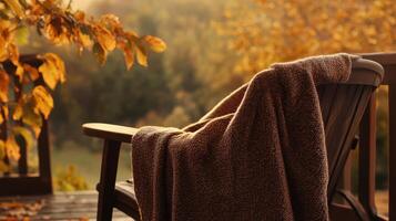 Cozy autumn scene with a poncho on a chair, earthy tones blending with the natural autumn setting, warm and inviting atmosphere. Autumn clothing photo