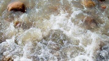 Wild sea, ocean with splashes on stones. Wave rolls onto shore. Top view, drone. Nature photo