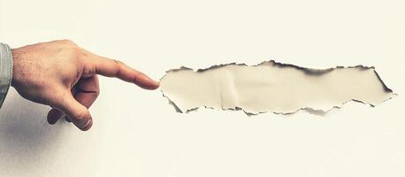 A business concept image shows a hand in a suit pointing at torn paper, symbolizing breakthrough and innovation. The minimalist, abstract design emphasizes creativity, disruption, and modern corporate photo