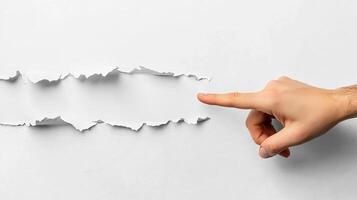 A business concept image shows a hand in a suit pointing at torn paper, symbolizing breakthrough and innovation. The minimalist, abstract design emphasizes creativity, disruption, and modern corporate photo