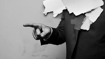 A business concept image shows a hand in a suit pointing at torn paper, symbolizing breakthrough and innovation. The minimalist, abstract design emphasizes creativity, disruption, and modern corporate photo