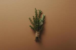 An isolated bundle of dried herbs tied with natural twine rests gracefully on a warm, earthy surface. The arrangement highlights the intricate textures and subtle colors of the herbs. photo