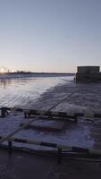 View of floating barge with cable on river. Clip. Floating barge behind ship near shore with snow on sunny winter day. Barge on cable floats behind boat on river video