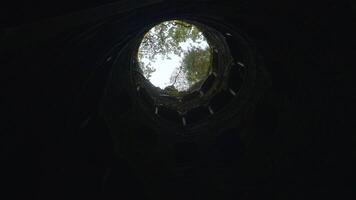 View from the basement. Action. A pipe that goes underground and green trees with sunlight are visible from above. video