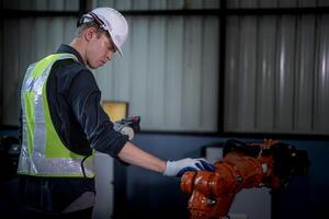 team engineers inspecting on machine with smart tablet. Worker works at heavy machine robot arm. The welding machine with a remote system in an industrial factory. Artificial intelligence concept. photo