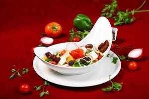Classic Greek Salad with Feta Cheese, onion, tomato, olive and capsicum served in bowl isolated on red background closeup side view of arabic food photo