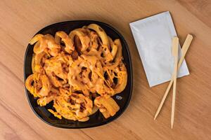 Loaded Curly Fries with Cheesy Sauce and Dipping Sauce served in plate isolated on wooden table top view fast food snacks photo