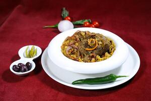 machboos laham or arabic lamb biryani served in pot isolated on red background side view of arabic food photo