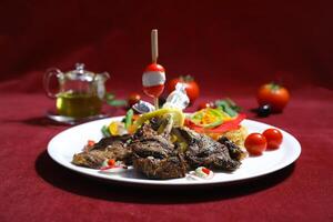 Grilled Lamb Chops with Mediterranean vegetables, including roasted tomatoes, zucchini, and red peppers served in plate isolated on red background side view of arabic food photo