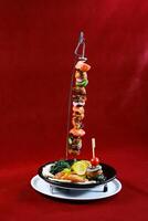 BBQ Chicken Shish tawook vertical skewer chicken tikka boti kabab with lemon, salad and biryani rice served in dish isolated on red background side view of arabic barbequed food photo