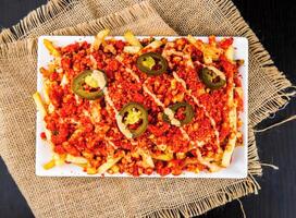 Spicy Cheetos Loaded Fries with Cheese, and Jalapenos served on tray isolated on napkin top view of fast food snacks photo