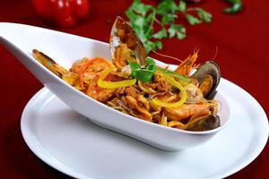 Seafood Spaghetti pasta include calms, shrimp, prawn and noodles served in dish isolated on red background closeup side view of italian food photo