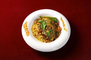 Chicken Kabsa biryani Rice with fried onion mint and coriander served in broth side view of arabic food on red background photo