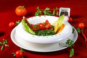 Tabbouleh Salad include bulgur wheat, tomatoes,vcucumbers combine, lemon juice and olive oi served in bowl isolated on red background top view of arabic food photo