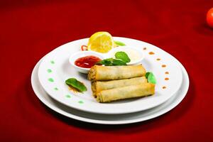 Crispy Spring Rolls with Dipping Sauces served in plate isolated on red background closeup side view of arabic food photo