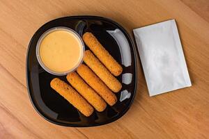 Crispy Mozzarella Sticks with Dipping Sauce served in plate isolated on wooden table top view fast food snacks photo