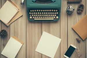 Retro typewriter on a wooden desk surrounded by paper, notebooks and a smartphone photo