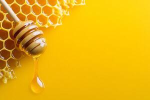 Honey dripping from a dipper with fresh honeycomb on a yellow background photo