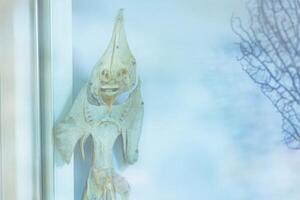 A unique fish artifact displayed on a window, showcasing intricate details in a coastal setting during the day photo