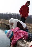 Children exploring a pond in early spring while a teenager looks on from the banks in a rural setting photo