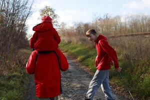 A family enjoys a sunny autumn day hiking on a dirt path surrounded by trees in a rural area photo