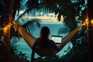 person relaxing in a hammock while working on a laptop surrounded by lush vegetation and a serene ocean view photo