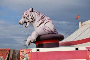 Large inflatable white tiger above a circus tent with a cloudy sky in the background. Represents circus and entertainment themes photo