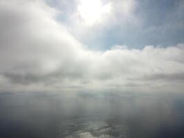 Aerial view. The drone flies over foggy and fluffy clouds. Blue sky sun and sea fog. Abstract aerial nature summer ocean sunset sea and sky background. Vacation, travel and holiday concept photo