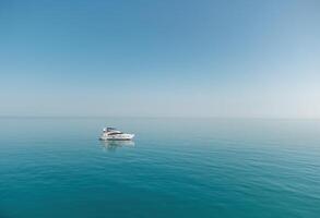 Aerial yacht on calm sea. Luxury cruise trip. View from above of white boat on deep blue water. Aerial view of rich yacht sailing sea. Summer journey on luxury ship. photo