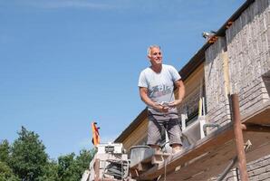the bricklayer makes the facade of the house from gray bricks with cement and plaster at the construction site. High quality photo