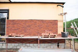a new House is being built, the beginning of brickwork with red bricks, building materials, a pattern of stones, a natural background. High quality photo