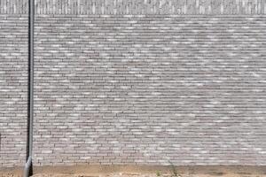 fragment Gray textured brick wall with built-in pipe for collecting rainwater from the roof, long and narrow modern bricks, horizontal Textured stone background, brickwork outside new building, photo