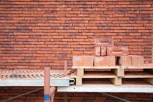 a new House is being built, the beginning of brickwork with red bricks, building materials, a pattern of stones, a natural background. High quality photo