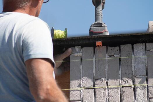 Builder aligning bricks on wall with level, tools in background, Concept of precision in construction work, photo