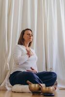 A woman sits on the floor with her eyes closed, practicing deep breathing exercises. She inhales and exhales slowly photo