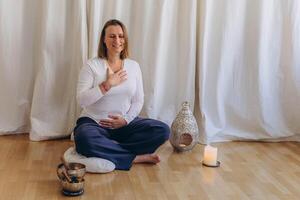 A woman sits on the floor with her eyes closed, practicing deep breathing exercises. She inhales and exhales slowly photo