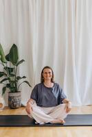 A woman sits on the floor with her eyes closed, practicing deep breathing exercises. She inhales and exhales slowly photo