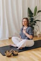 A woman sits on the floor with her eyes closed, practicing deep breathing exercises. She inhales and exhales slowly photo