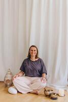 A woman sits on the floor with her eyes closed, practicing deep breathing exercises. She inhales and exhales slowly photo