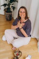 A woman sits on the floor with her eyes closed, practicing deep breathing exercises. She inhales and exhales slowly photo