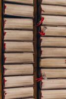 top-down view of rows of old books with worn pages and red bookmarks, neatly arranged on wooden shelves. Warm, cozy lighting. photo