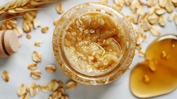 natural oatmeal face scrub with honey and oats in a jar on a white background for skincare routine photo