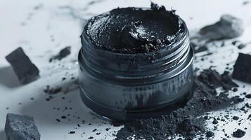 natural charcoal face scrub in a jar, showcasing activated charcoal bits on a clean white surface photo