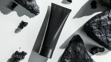 activated charcoal face cream tube with charcoal pieces on white background for skincare routine. photo