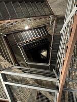 A spiraling metal staircase inside a church tower, leading upwards to the top. photo