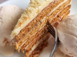 Close up of a delicate piece of cake and ice cream,on a plate with a fork photo