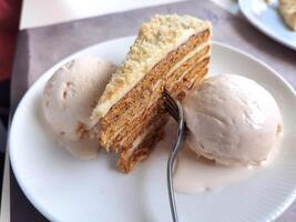 Close up of a delicate piece of cake and ice cream,on a plate with a fork photo