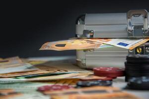 Euro banknotes and poker chips lay on a table next to a closed, silver carrying case photo