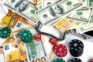 A close-up image of various poker chips, dice, and US dollar bills and Euro banknotes scattered on a white surface photo